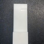 A white plastic tube with a hole in it.