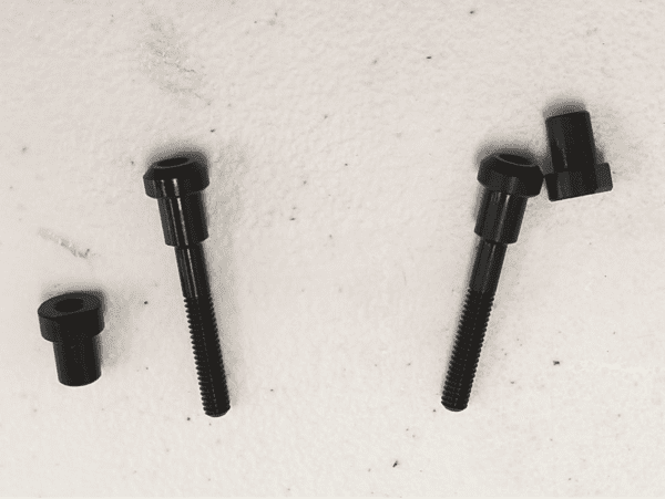 A set of four black bolts sitting on top of a wall. A set of four black bolts sitting on top of a wall.