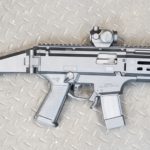 A silver gun with a red dot sight on it.
