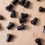 A bunch of black plastic nuts sitting on top of a table.