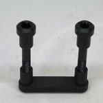 A black plastic object with two small nuts.