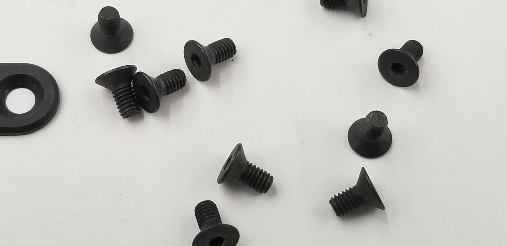 A bunch of black nuts and bolts on the ground