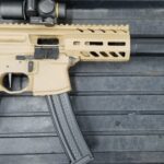A rifle with an attached scope and a black handle.