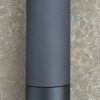 A black bottle sitting on top of a cement floor.
