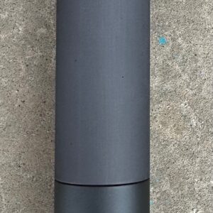 A black bottle sitting on top of a cement floor.